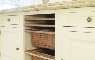 White kitchen drawers and straw storage baskets below kitchen bench