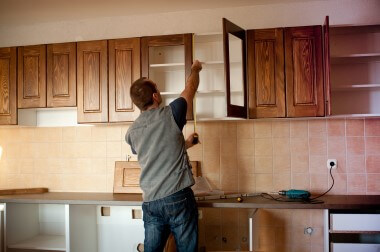 Man measuring kitchen cupboard above bench for new doors